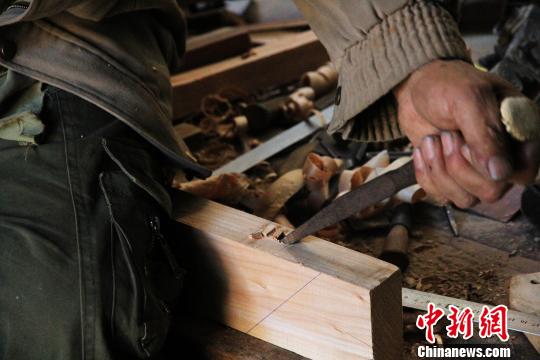 5月4日,在历城明式传统家具制作技艺第六代传人徐光祥家中,徐光祥正在为桌案板凿卯眼。 郝学娟 摄